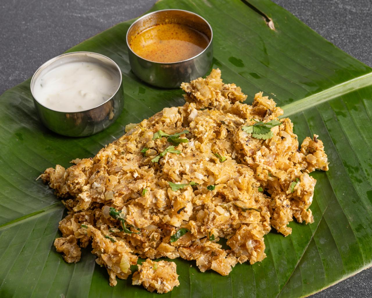 Chicken kothu parotta being chopped with two blades on a hot tawa